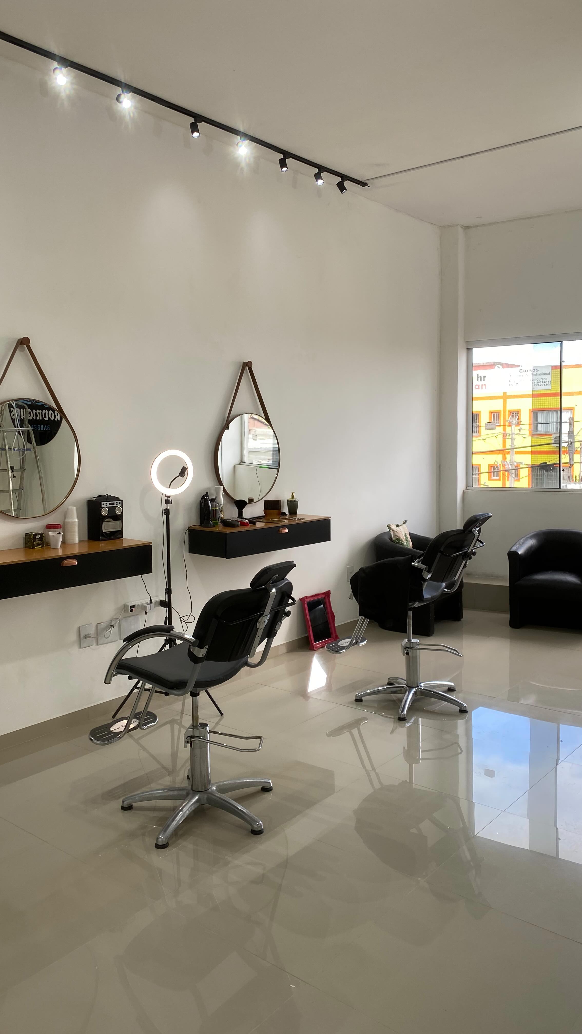 Interior da Barbearia Rodrigues mostrando cadeiras profissionais, espelhos e ambiente moderno